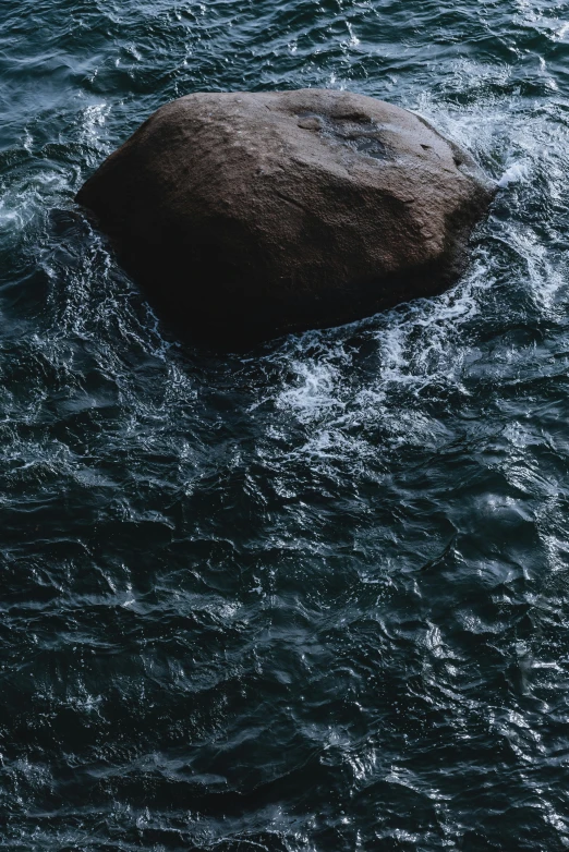 a large rock sitting in the middle of water