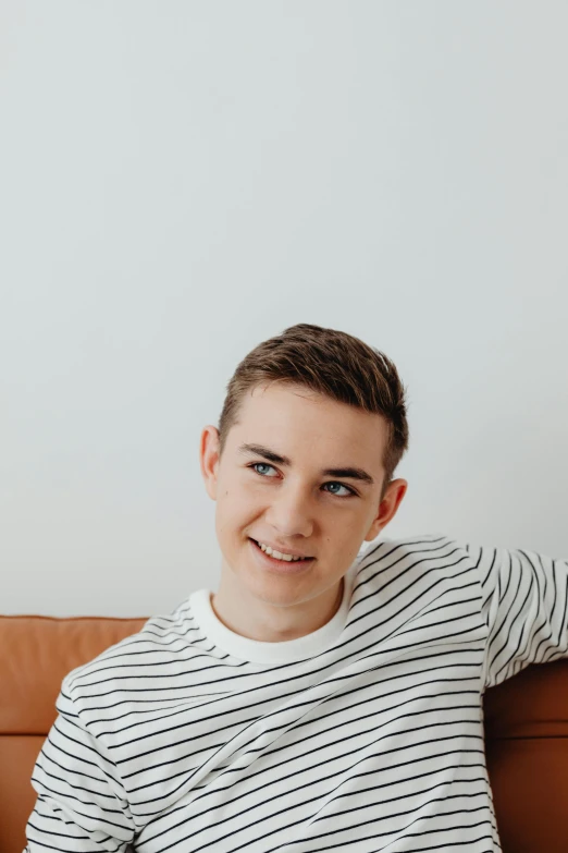 a young man sitting on the couch smiling for the camera