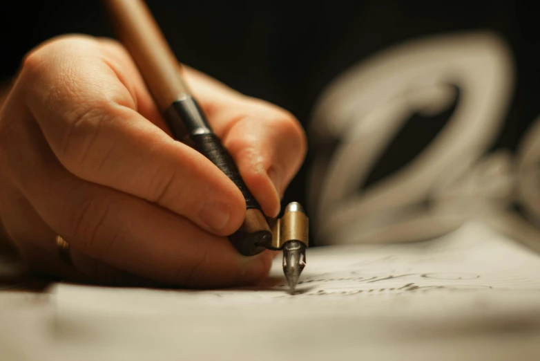 a man's hand holding a pen writing on paper with a swirl design behind it