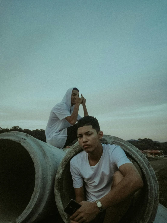 a couple standing next to pipes at sunset