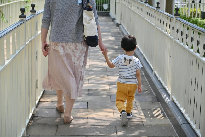 a woman and child are walking on a walkway