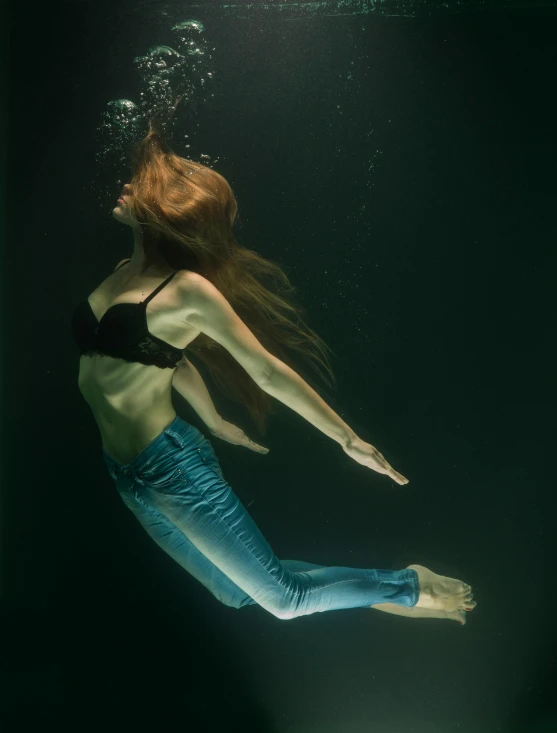 a woman wearing jeans, top and swim gear in the water