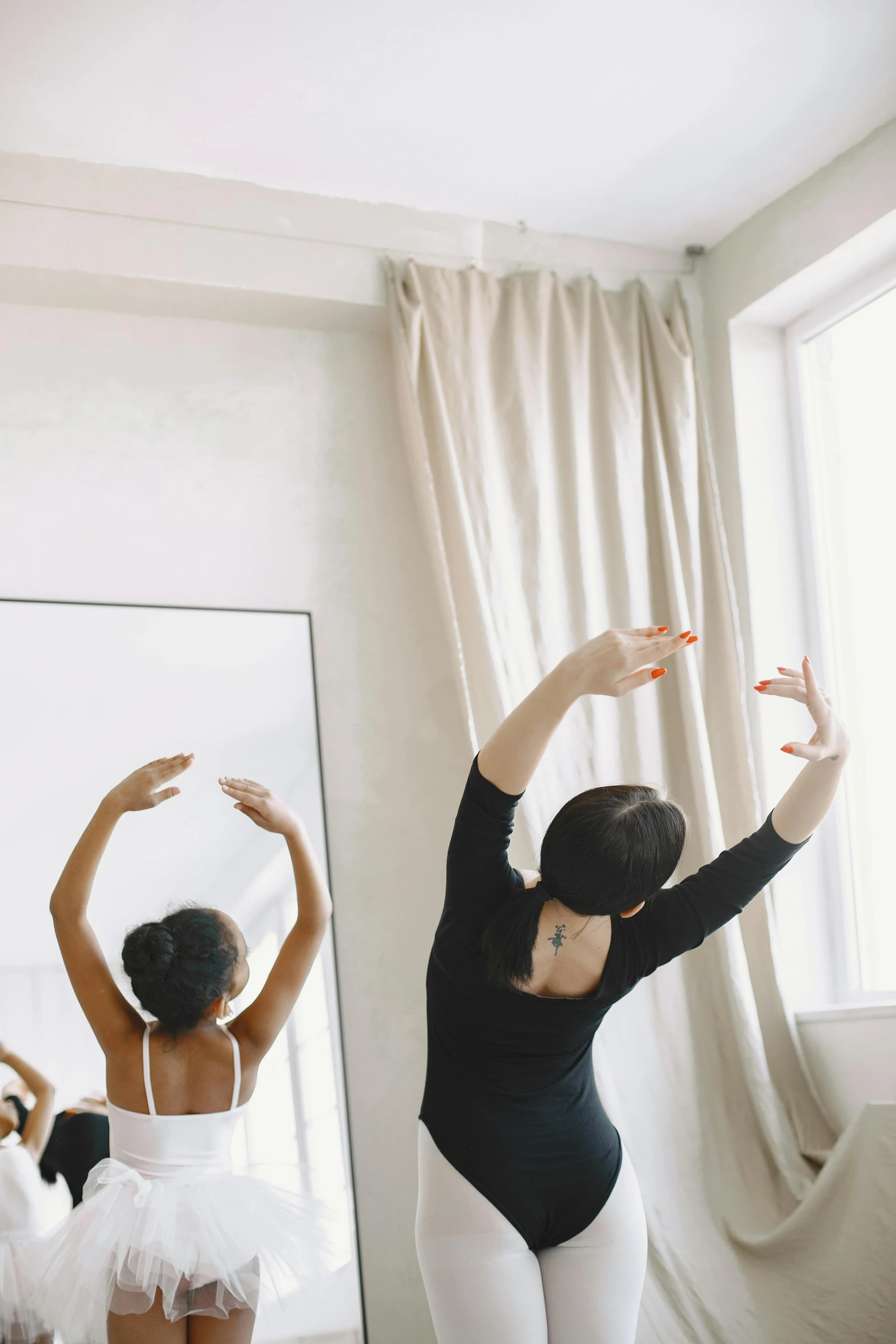 two ballerinas standing near a window and a mirror