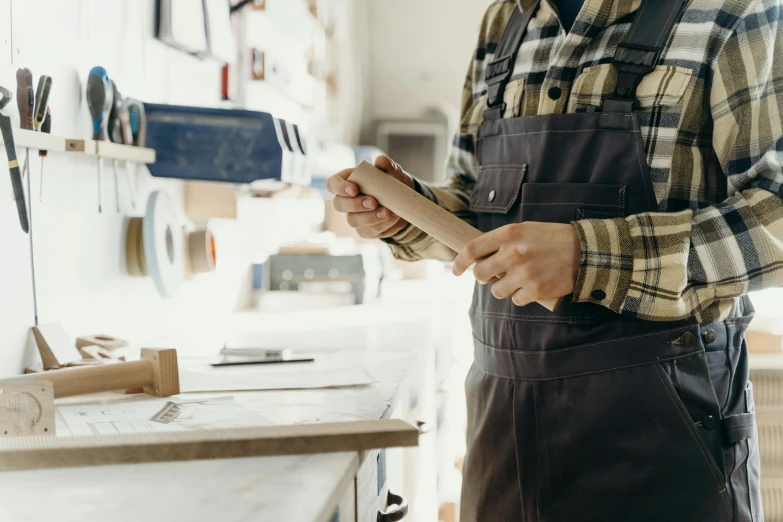 a worker standing in front of a workbench holding a rolling pin