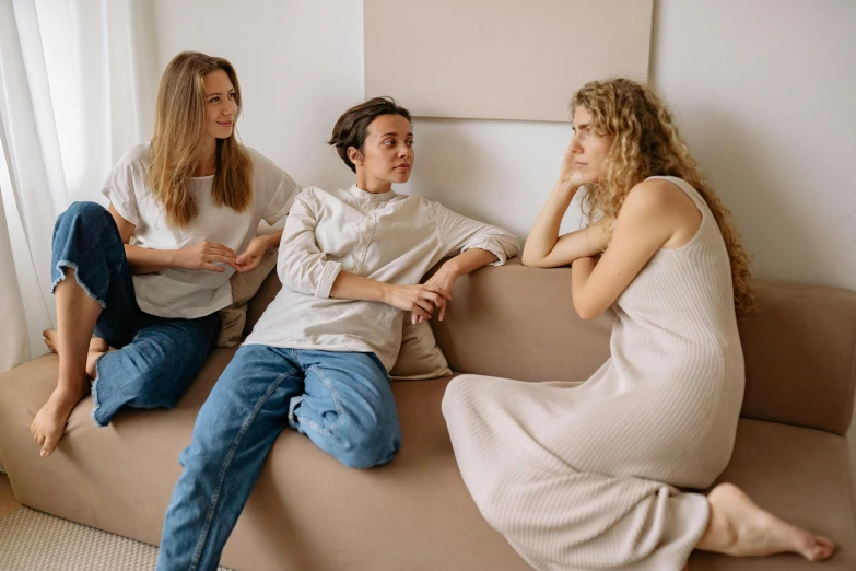 three people sitting on top of a couch with one another