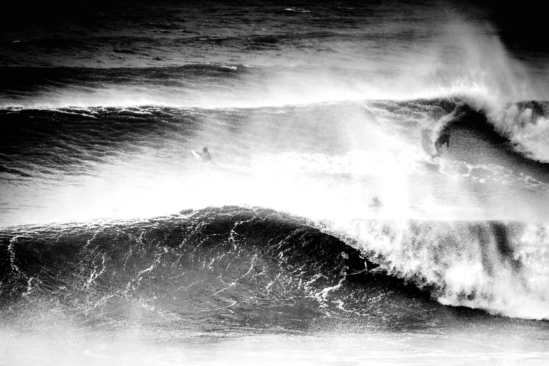 a surfer rides a large ocean wave in black and white