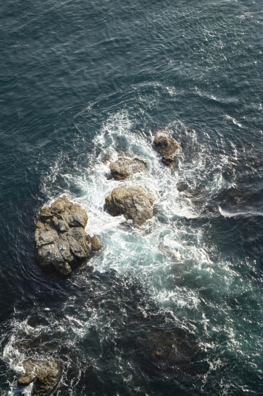 rocks are in the ocean with water behind them
