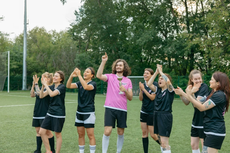 several girls are giving a high five standing in a soccer field