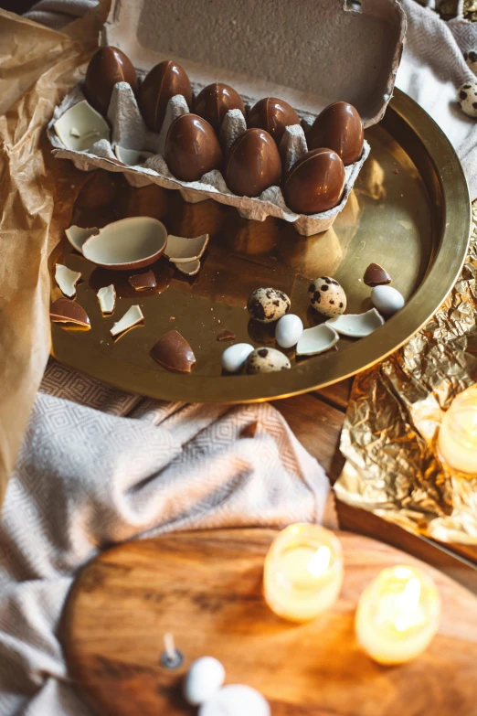 some chocolate eggs on a tray with candles