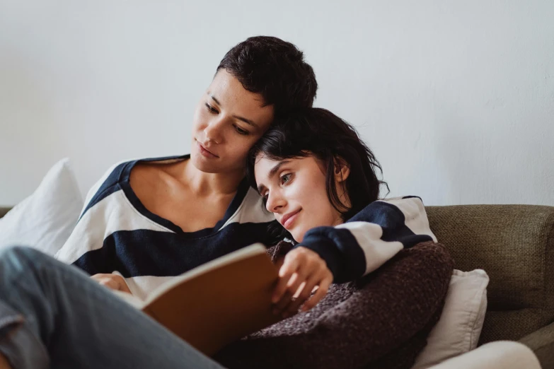 woman sitting on a couch next to a woman with a book