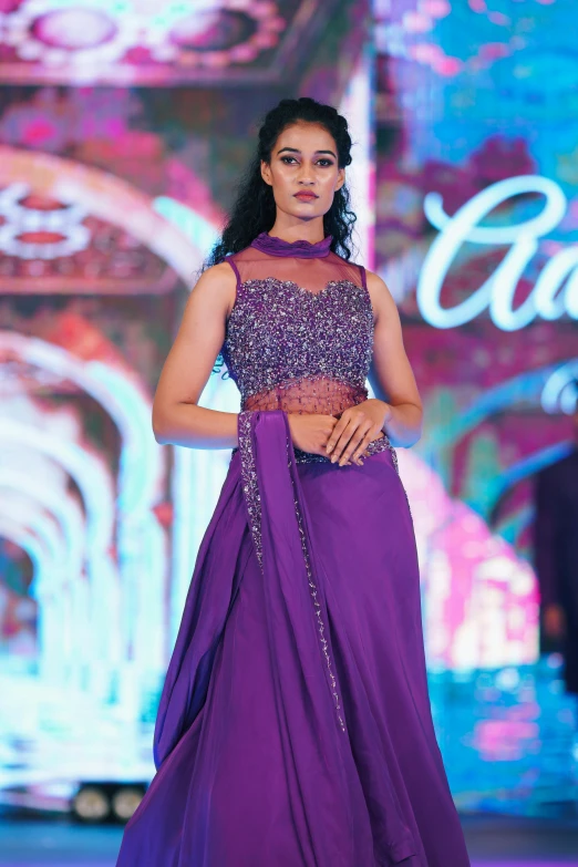 an indian fashion designer in purple dress on the runway