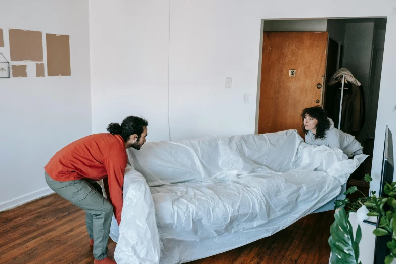 a man and woman packing mattresses up in an empty room