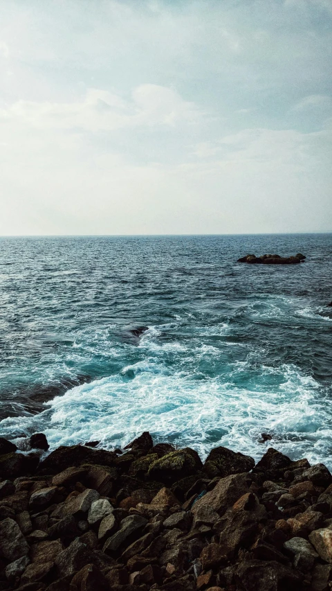 a lone boat out in the open ocean with rocks and water around it