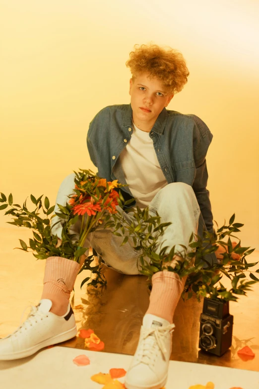 the boy is sitting on a small pot with flowers