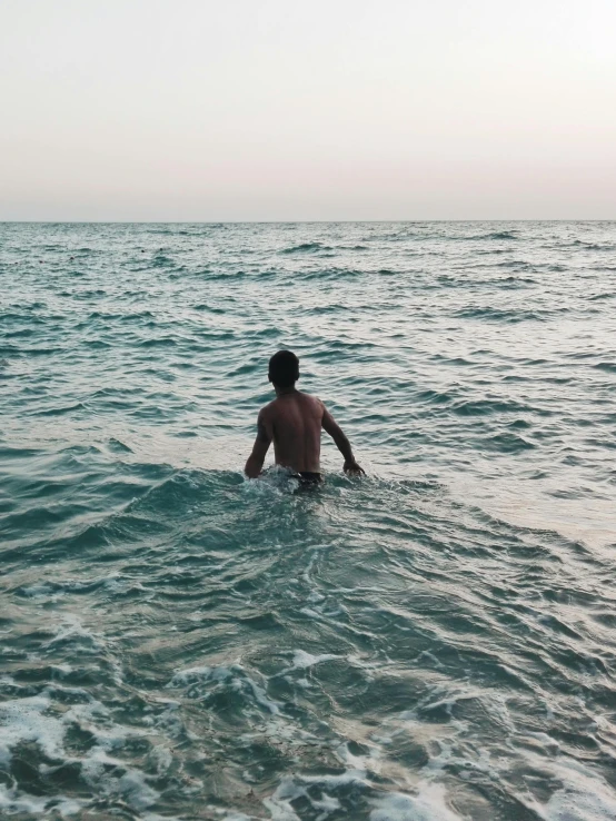 man wading out into the ocean from the surf