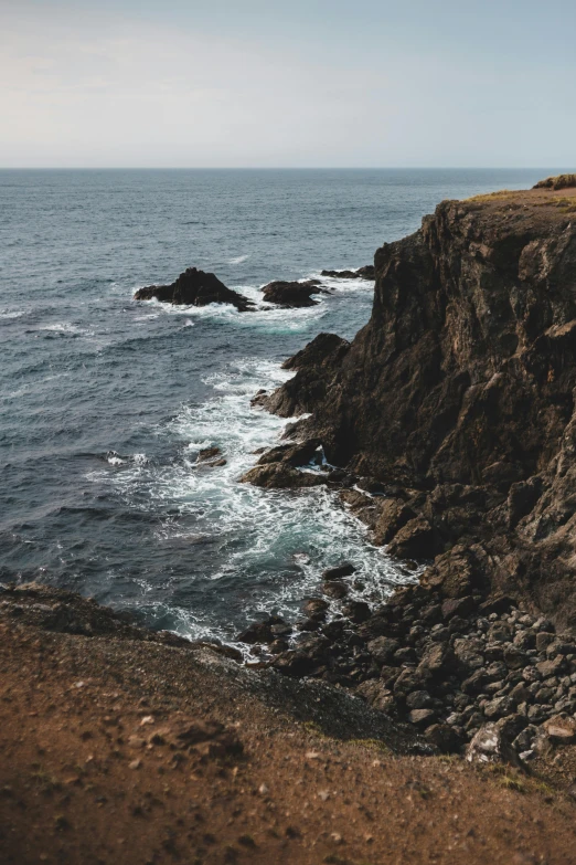 a big cliff by the ocean with a bunch of rocks