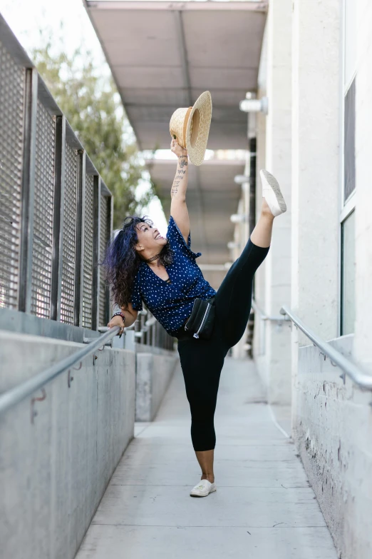 a woman wearing black pants is doing yoga in an alley