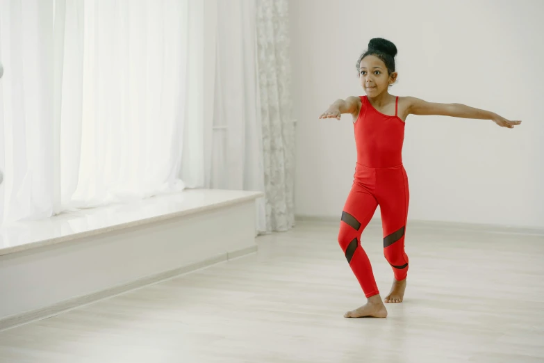 a little girl is performing an exercise in the room