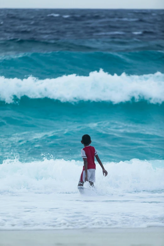 a  walking through the water towards an ocean wave