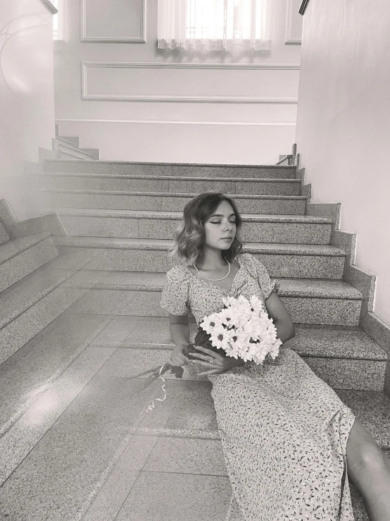 a woman sitting on a flight of stairs with a bouquet