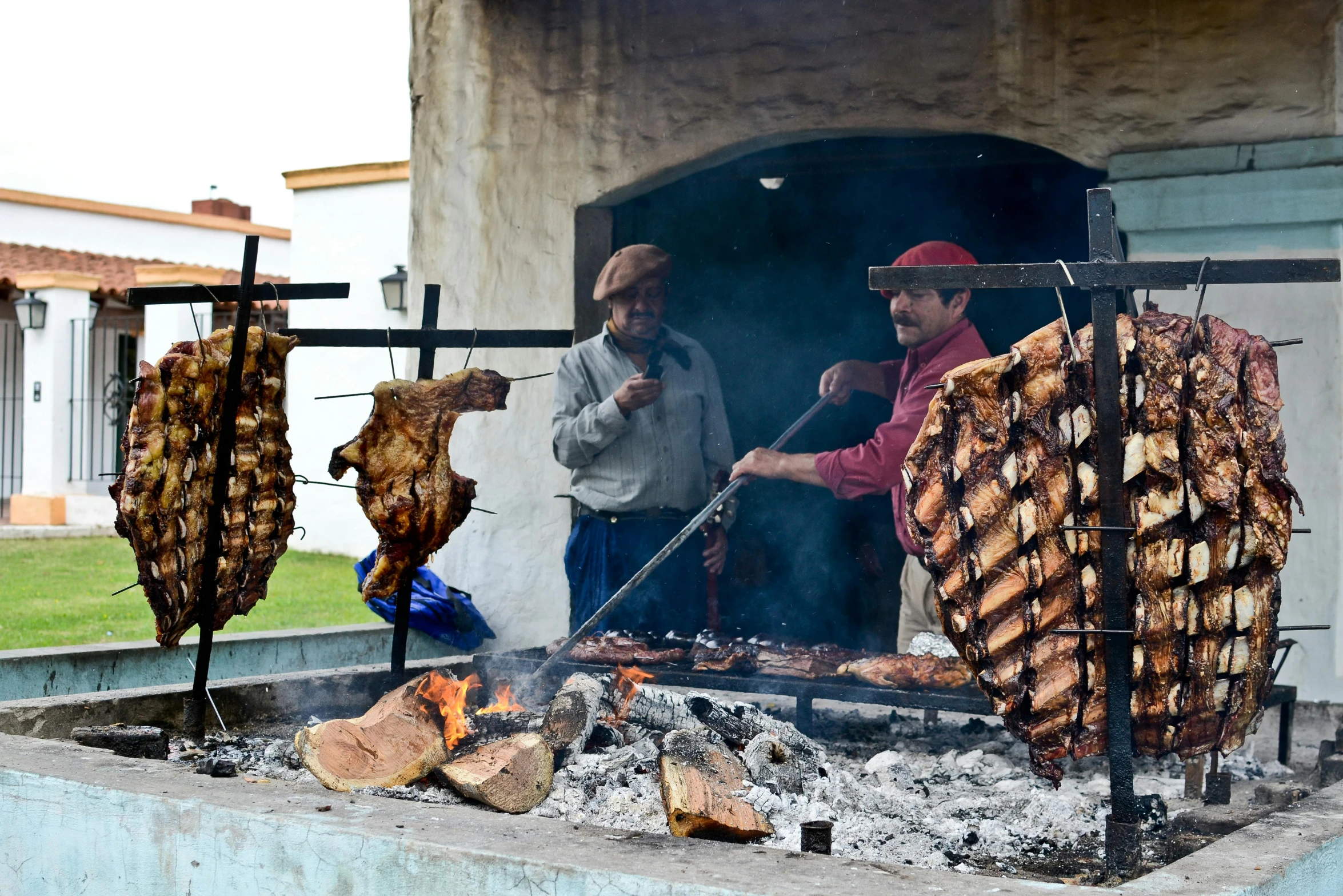 the men are grilling  dogs and sausages outside