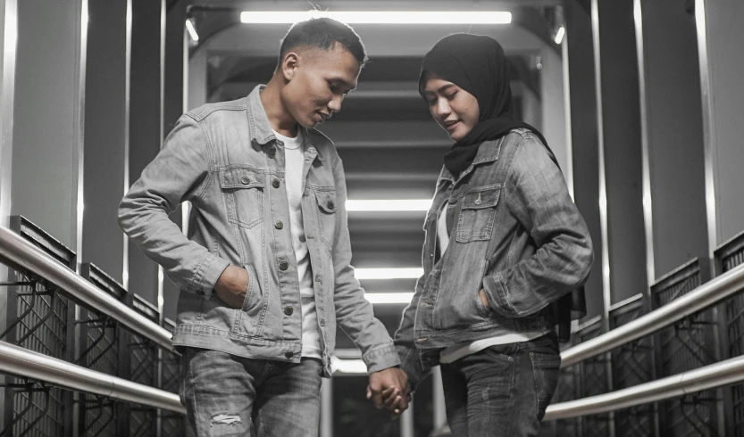 two people with their skateboards standing in a building