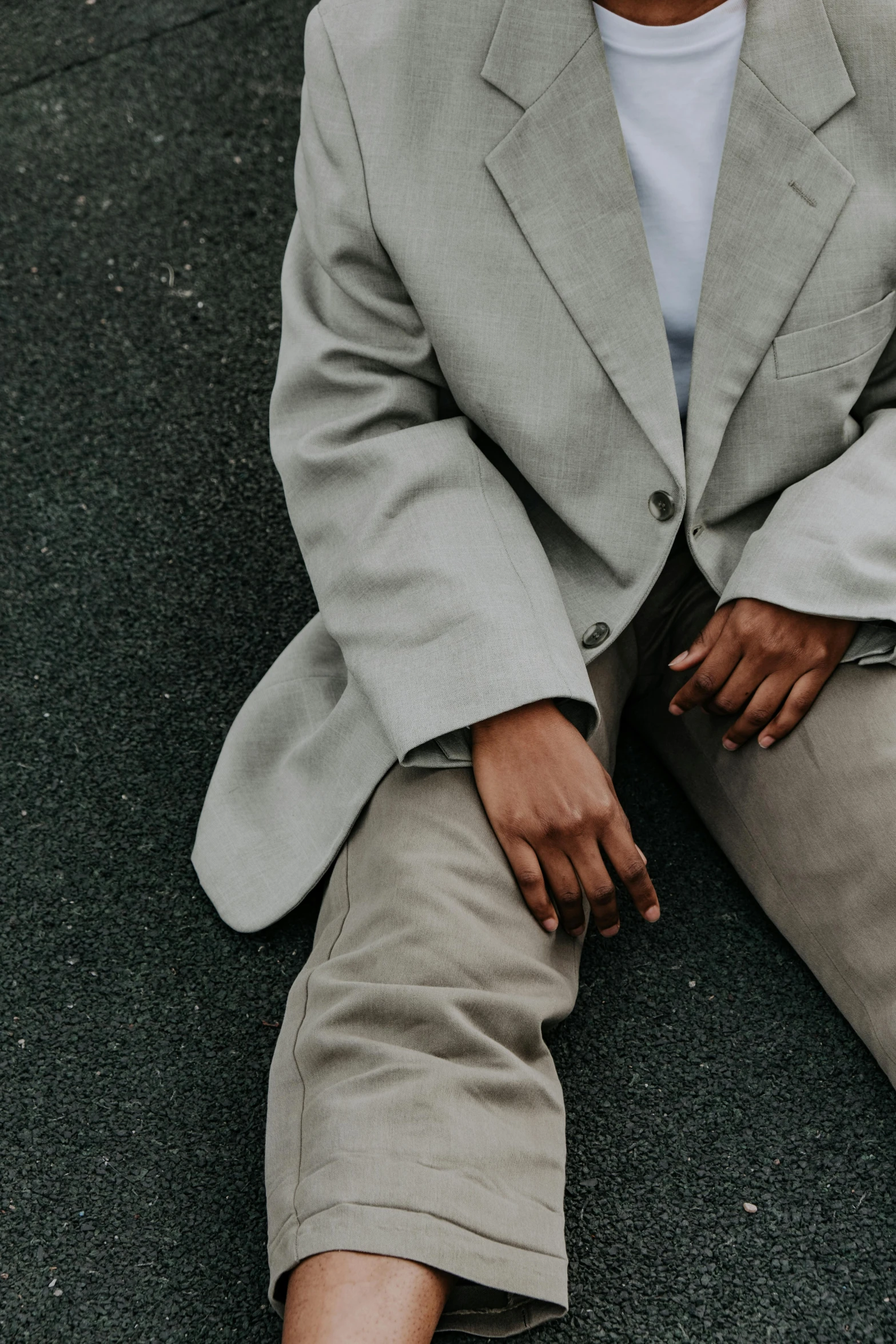 a black man in a white shirt and gray suit sitting on the ground