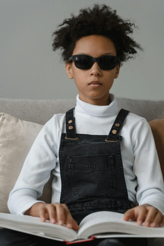 a  in sunglasses sitting on top of a couch while reading a book