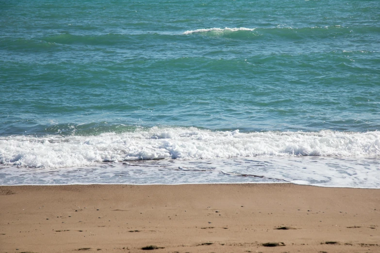 there is a person walking on the beach next to the ocean