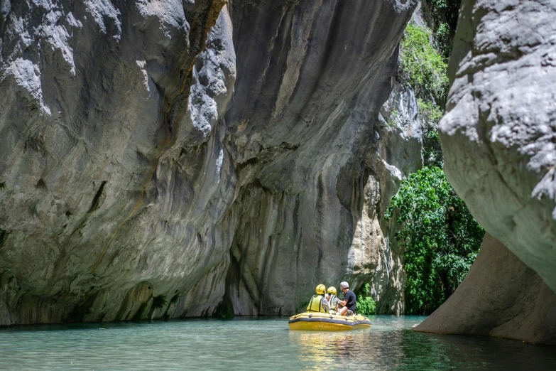 two people are on a yellow raft floating down a river