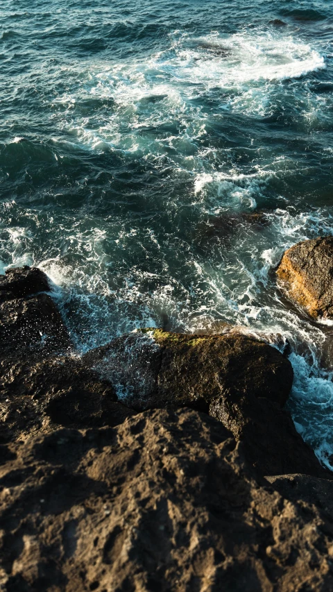 the waves are breaking over the rocks at the beach