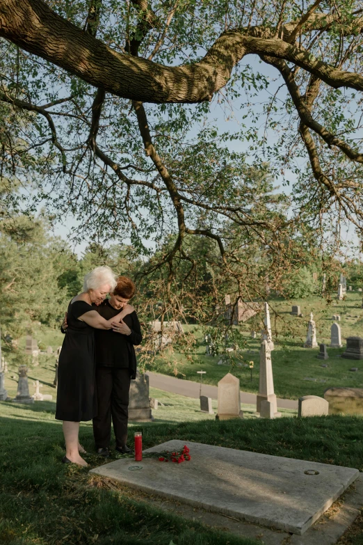 two people hugging each other in front of a tree