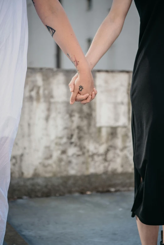 two people hold hands and stand by an old building