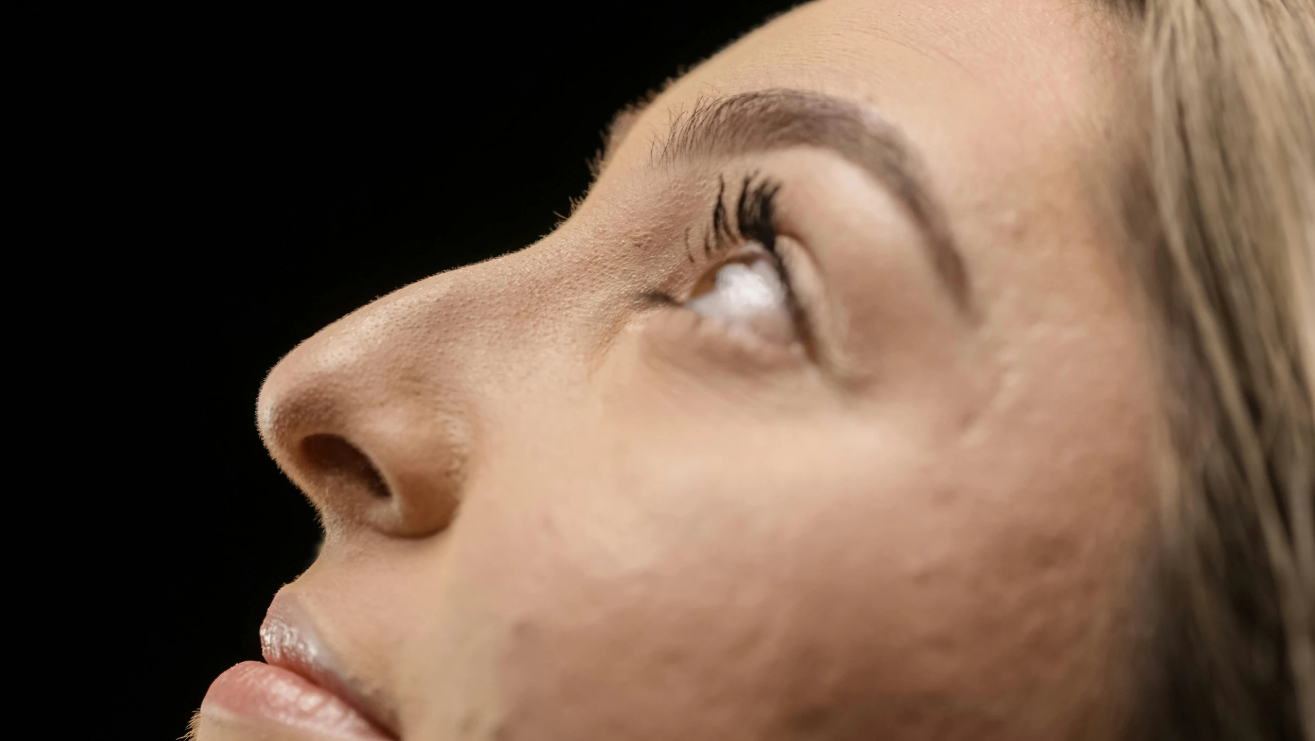 a woman with an eyeliner looks up while she's looking up