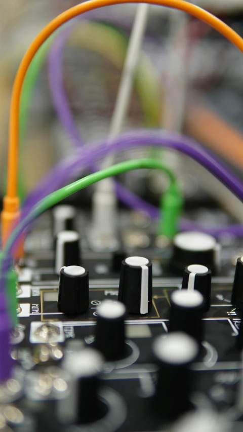 a multicolored mixer board with multiple different colored cords