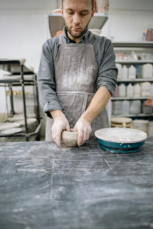 the man is kneading dough while wearing a apron