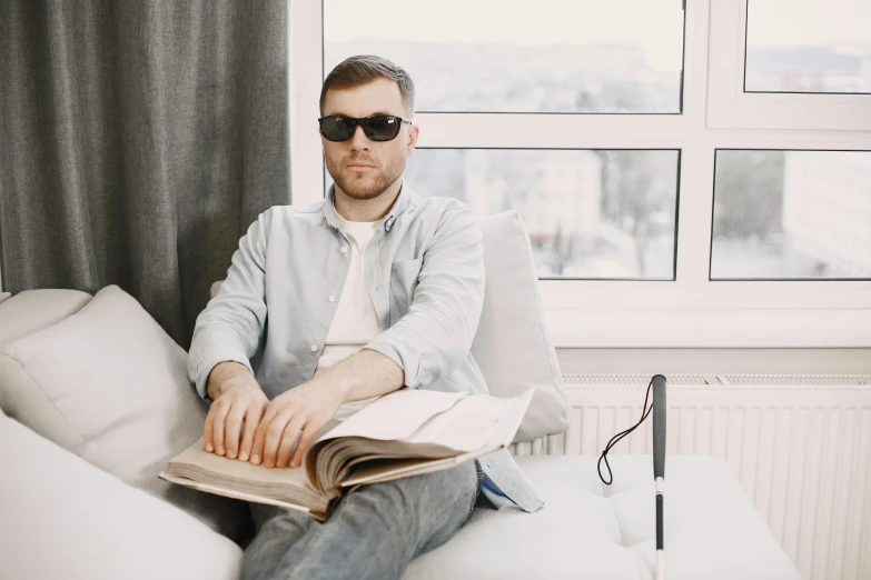 a man sitting on a couch while holding a book