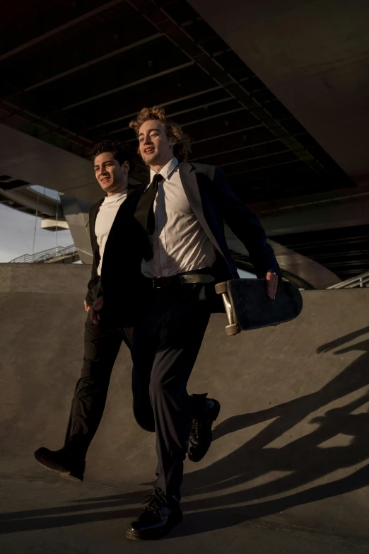 two young men pose for a picture underneath a bridge