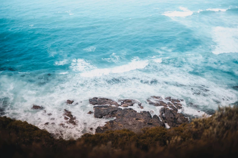 aerial view looking down over the ocean towards rocks