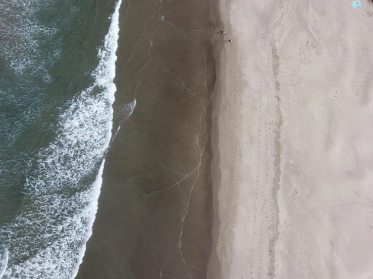 two people walking on a beach with an ocean in the background