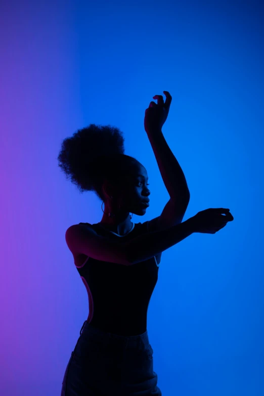 a woman standing in front of a purple light holding her hand out