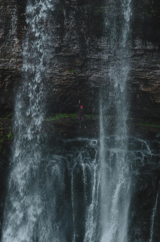 a man stands on the edge of a large waterfall as it erupts