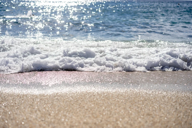 the ocean has white waves on the sand