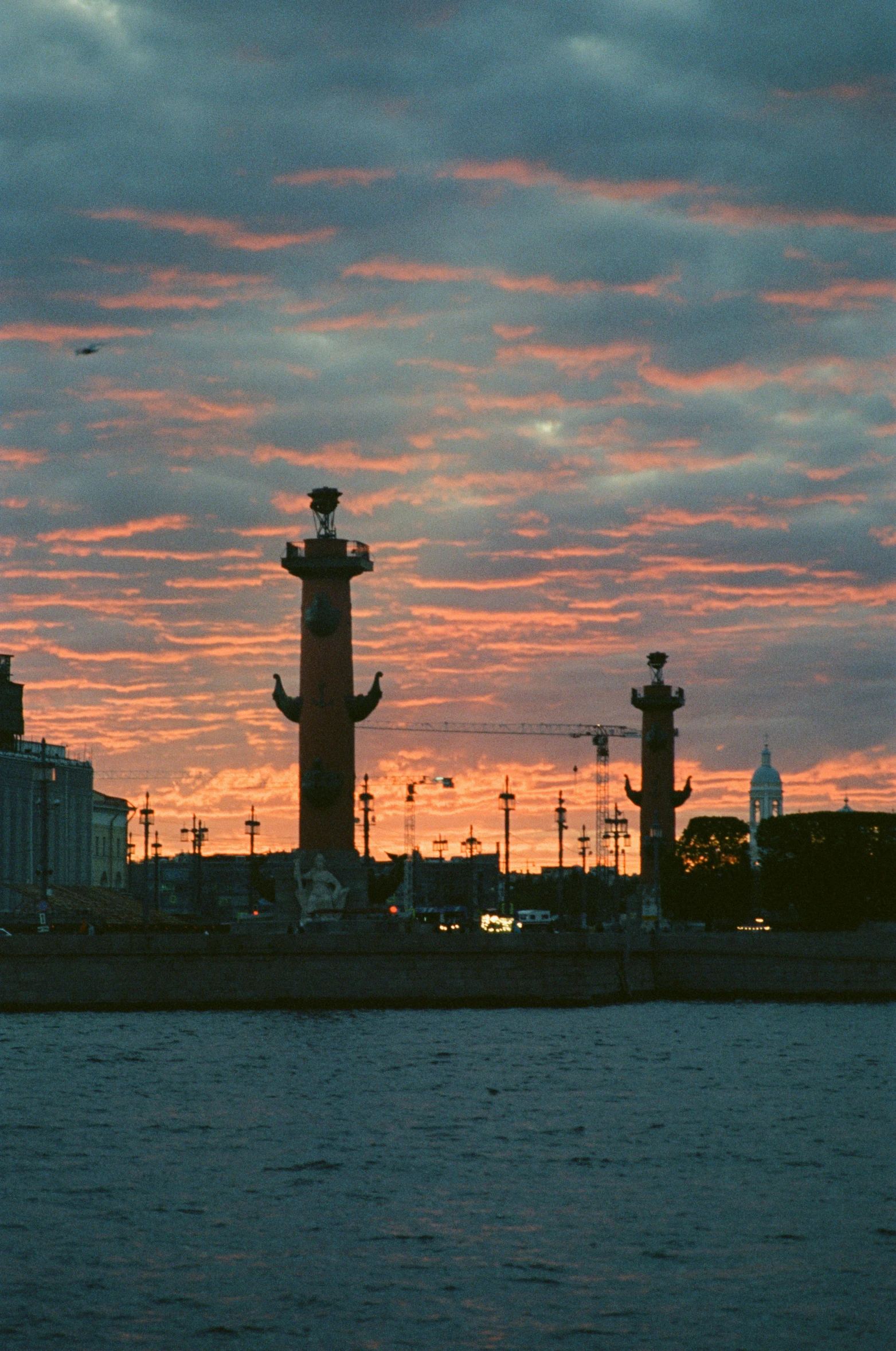 clouds cover the skyline and silhouettes a lighthouse on a pier