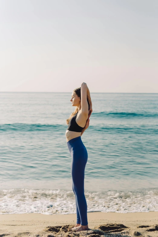 a woman doing yoga poses on the beach