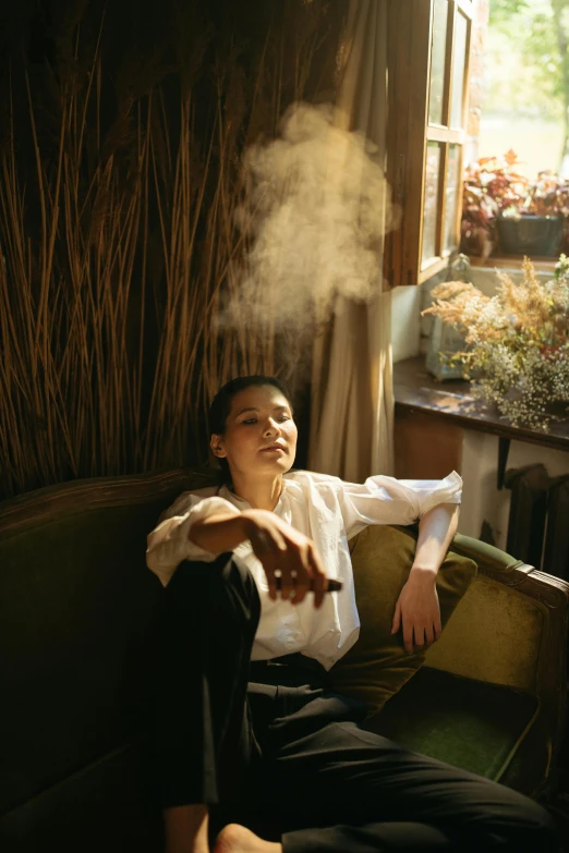 a woman smoking a cigarette sitting on a sofa