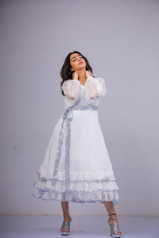 woman in white dress looking up while holding her hands near the face