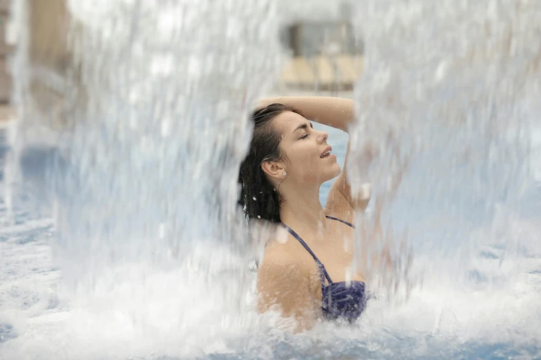 a woman splashes water while posing under a splasher