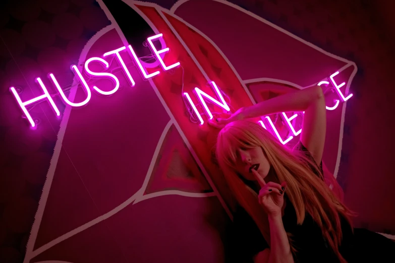 woman in front of hustle in sign with purple background