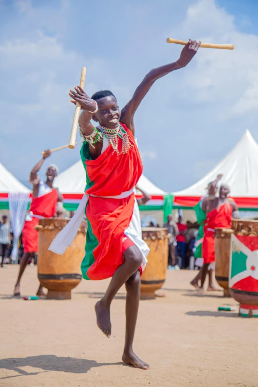 an african american man in red and white outfit is holding a bamboo stick